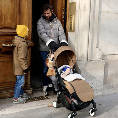 bébé dans chancelière poussette papa parle avec son grand fils