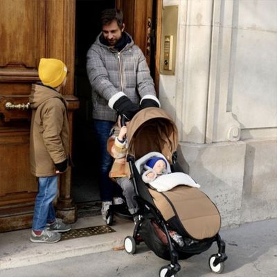 bébé dans chancelière poussette papa parle avec son autre fils