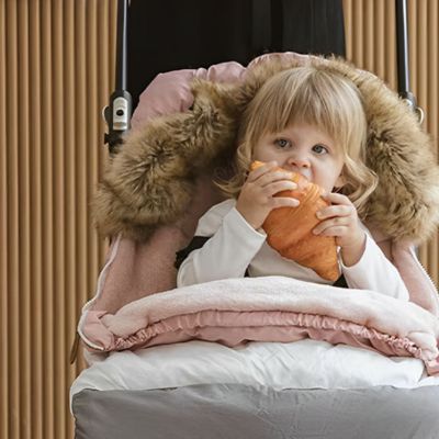 fillette mange dans chancelière poussette