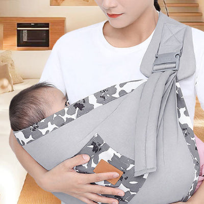 main maman soutient bebe dans echarpe de portage